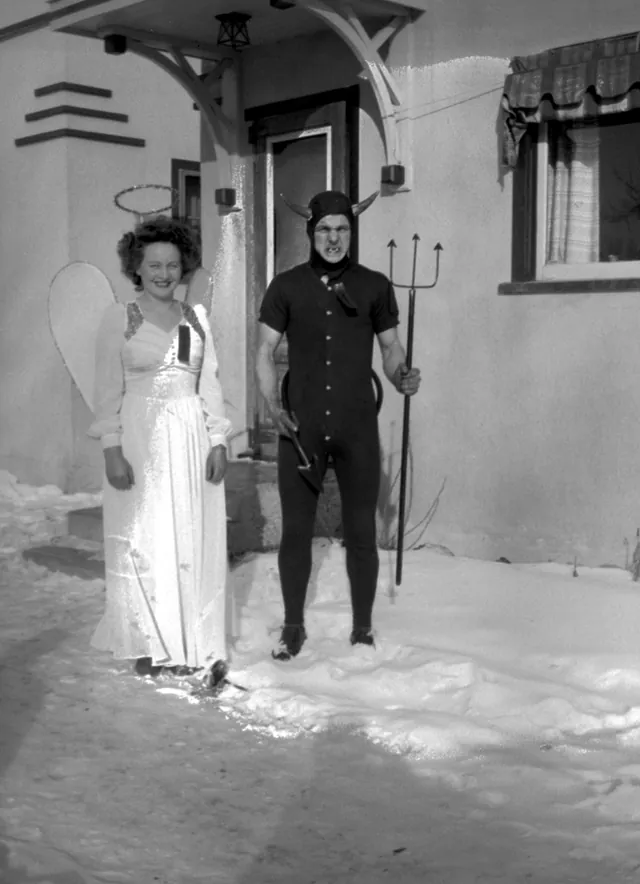 A woman dressed as an angel and a man dressed as a devil with a pitchfork, standing in the snow in Claresholm in 1949