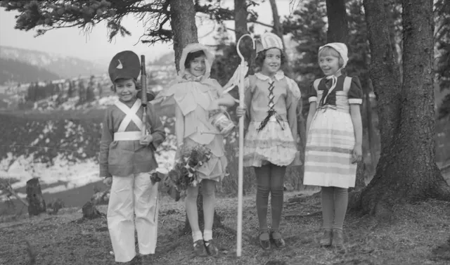 Four children in costumes standing among pine trees in Mountain Park in 1934
